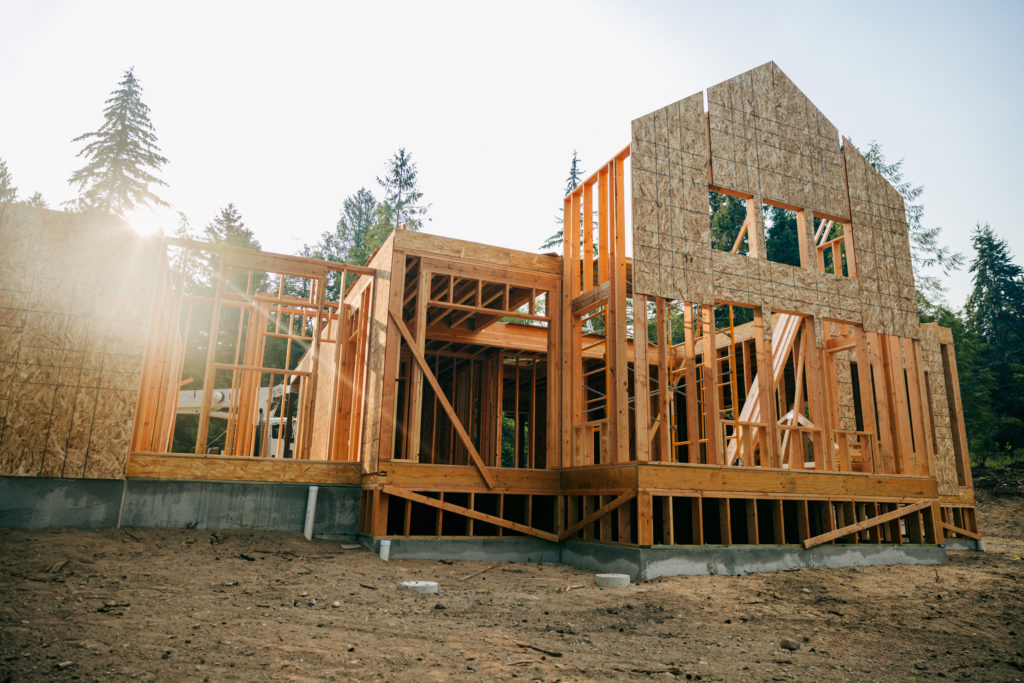 Bare plywood and beams as a new house is framed up from the foundation.  High lumber costs have affected the building process.  Shot in Washington state, USA at sunrise.